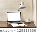 A modern workspace featuring a laptop, a desk lamp, a cup of coffee, and notepads.  129513330