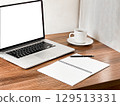 A modern workspace featuring a laptop, a blank notebook, a pen, and a cup of coffee on a wooden desk.  129513331