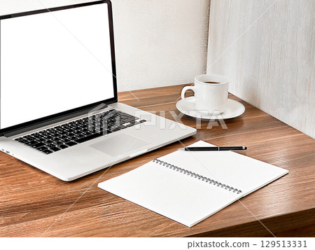 A modern workspace featuring a laptop, a blank notebook, a pen, and a cup of coffee on a wooden desk. A modern workspace featuring a laptop, a blank notebook, a pen, and a cup of coffee on a wooden desk. 129513331