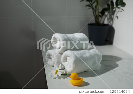 Soft White Towels Arranged on a Bathroom Countertop With a Daisy and Rubber Duck for Decoration Soft White Towels Arranged on a Bathroom Countertop With a Daisy and Rubber Duck for Decoration 129514054