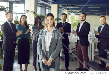 Happy smiling CEO in front of diverse office coworkers, subordinates in modern workspace applauding 129514304