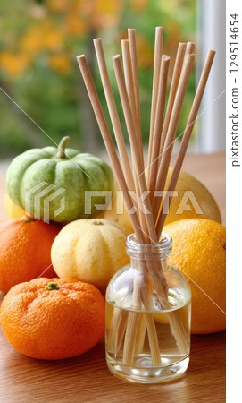 Autumn decorations create a cozy atmosphere with pumpkins, dried oranges, candles, and an inviting aromatherapy diffuser nearby 129514654