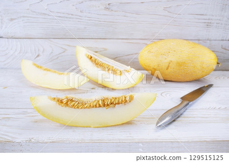 Slices ripe melon on white wooden background, close-up. Healthy eating, vegetarian food. Vitamin dessert. Slices ripe melon on white wooden background, close-up. Healthy eating, vegetarian food. Vitamin dessert. 129515125