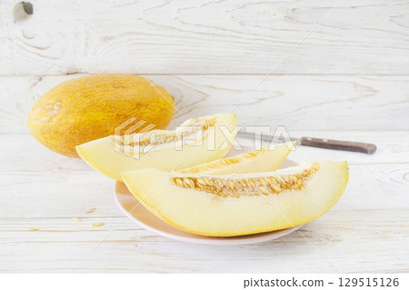 Slices ripe melon on white wooden background, close-up. Healthy eating, vegetarian food. Vitamin dessert. Slices ripe melon on white wooden background, close-up. Healthy eating, vegetarian food. Vitamin dessert. 129515126