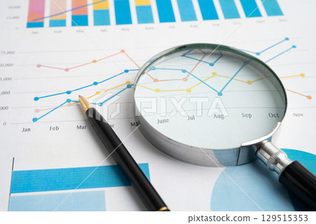 Magnifying glass on data business graphs paper. 129515353