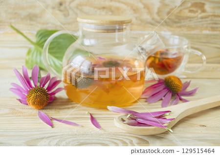 Echinacea flower tea in a glass teapot on a wooden background. Medicinal herbal tea from echinacea flowers. Echinacea flower tea in a glass teapot on a wooden background. Medicinal herbal tea from echinacea flowers. 129515464