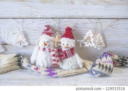 Christmas background. Knitted wool scarf with ornament on wooden background, illumination and handmade Christmas decorations. Top view with space for text. Christmas background. Knitted wool scarf with ornament on wooden background, illumination and handmade Christmas decorations. Top view with space for text. 129515518
