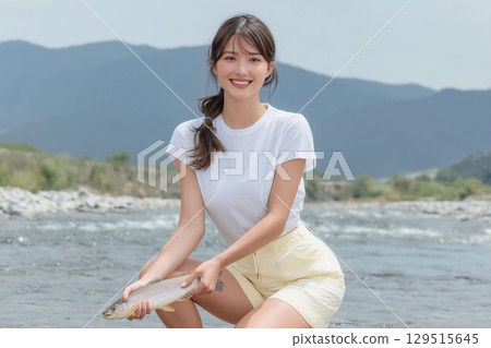 A smiling woman catching sweetfish in a clear river 129515645