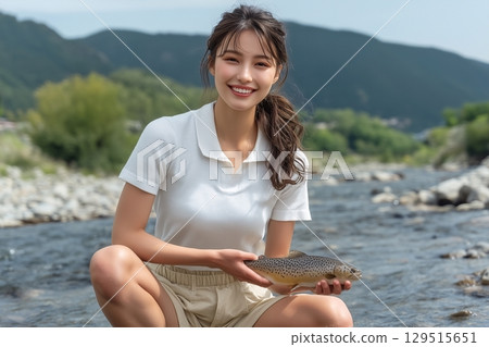 A smiling woman catching sweetfish in a clear river 129515651