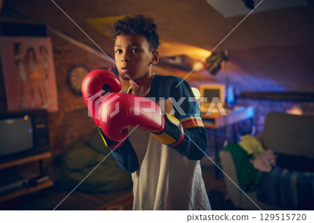 Teen boy in boxing stance in vintage attic room 129515720