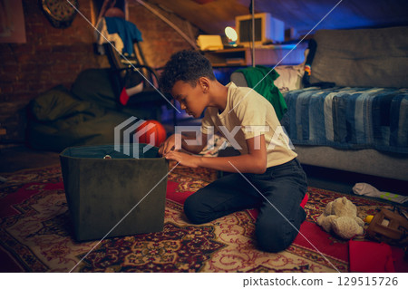 Boy looking into green storage box indoors 129515726