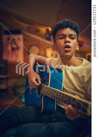 Boy singing and playing guitar passionately in vintage attic space 129515731