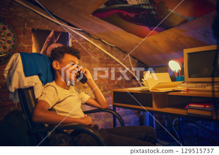 Smiling boy talking on vintage phone at desk 129515737