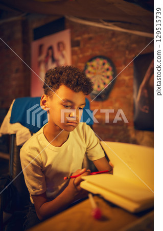 Boy looking down at notebook while holding pencil 129515739
