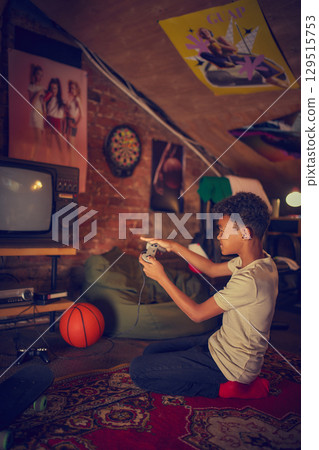 Boy playing retro video game in vintage attic room Boy playing retro video game in vintage attic room 129515753