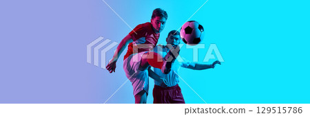 Dynamic soccer action between two players in vibrant blue and purple lighting with ball mid-air. Banner Dynamic soccer action between two players in vibrant blue and purple lighting with ball mid-air. Banner 129515786