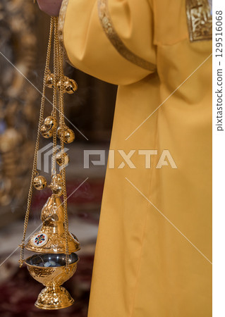 Golden Censer with Incense Smoke in Orthodox Christian Church Ritual, Priest's Vestment, Yellow Fabric, Religious Ceremony Detail 129516068