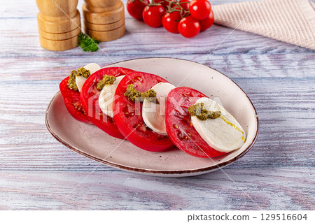 Italian Caprese salad with tomato, mozarella and pesto 129516604