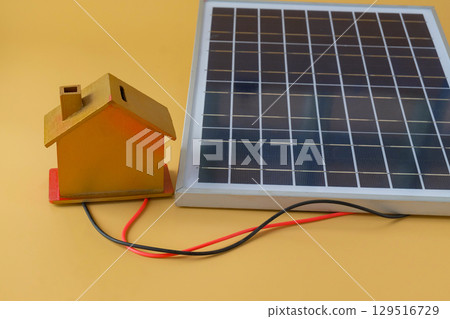 Composition with solar panel and model house on background. Composition with solar panel and model house on background. 129516729