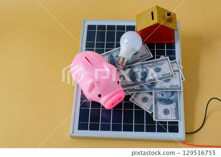 Composition with solar panel, led lamp, money and piggy bank on texture background. 129516755