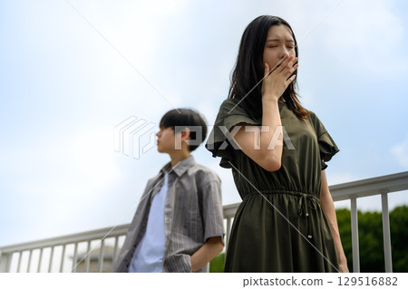 一位女士倚靠在籬笆上沉思，一位男士在一旁注視著 129516882