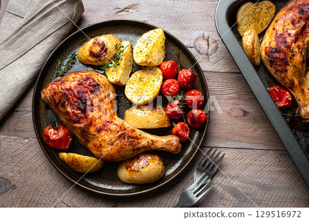 Oven roasted chicken leg quarter with potatoes, tomatoes 129516972