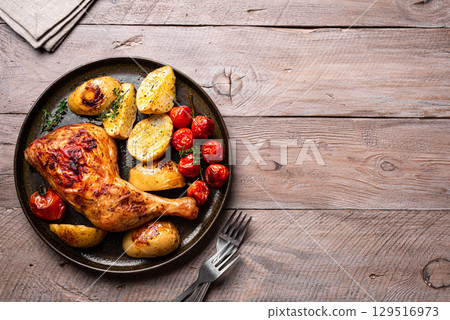 Oven roasted chicken leg quarter with potatoes, tomatoes 129516973