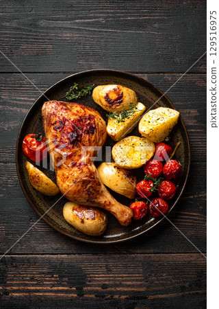 Oven roasted chicken leg quarter with potatoes, tomatoes 129516975