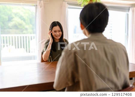 The daily life of a man and woman facing each other in a bright dining room 129517408