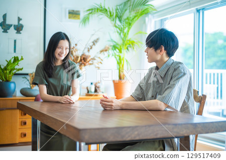Two people chatting in the dining room with natural light streaming in 129517409