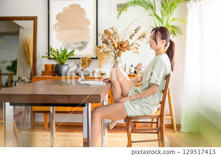 A woman on holiday stretching her legs and looking at her smartphone 129517413