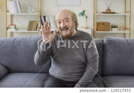 Senior man waves hello, having video call on laptop talking with relatives, smiling aged grandfather 129517433