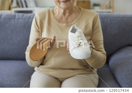 Close-Up Of Senior Woman Holding Shoe And Insole At Home Close-Up Of Senior Woman Holding Shoe And Insole At Home 129517434