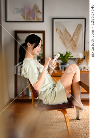 A woman sitting in a chair and enjoying using her smartphone 129517546
