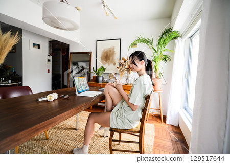 A woman relaxing at home using a laptop 129517644