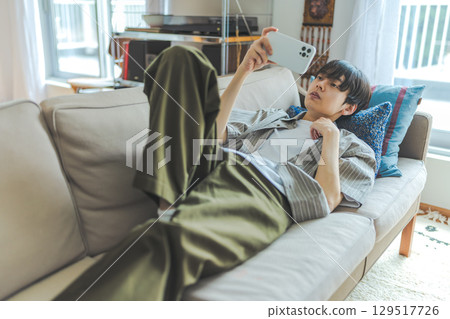 一名男子躺在沙發上觀看視頻 129517726