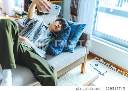 一名男子在沙發上休息時用智慧型手機自拍 129517745