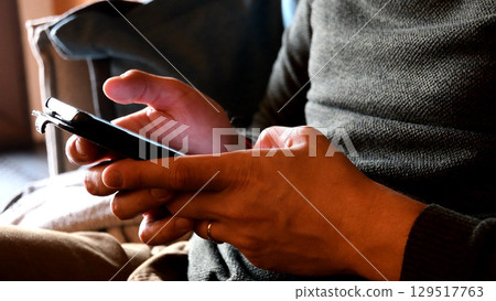 Male hands tapping and swiping his smartphone closeup 129517763