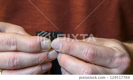 Male fingers hold PCI Express power supply connector for graphics card 129517769