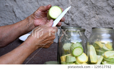 Granny slices raw squashes for homemade canning of healthy vegetable food 129517782