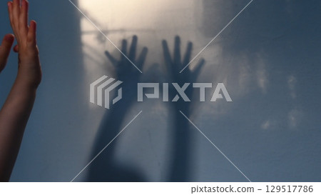 Defocus shadows of kid hands on stucco wall surface with copy space. Halloween concept Defocus shadows of kid hands on stucco wall surface with copy space. Halloween concept 129517786