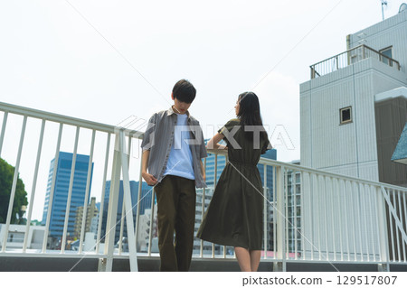 Back view of a man and woman looking at the city from a rooftop Back view of a man and woman looking at the city from a rooftop 129517807