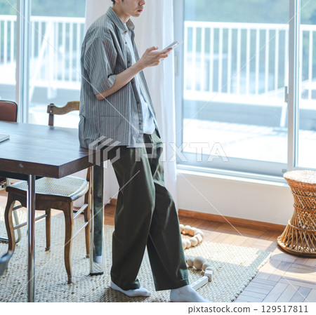 A man walking by the window while looking at his smartphone 129517811