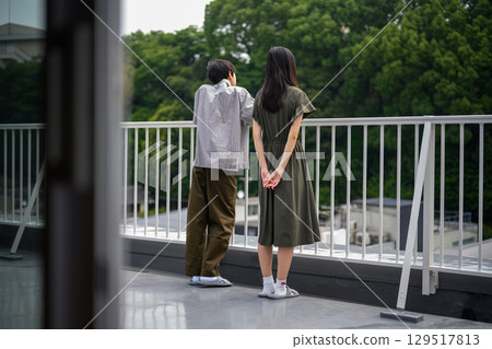 A youthful scene of two people standing side by side looking out at the outdoors 129517813