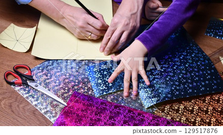 Mother and kid hands hobby crafting with glowing colorful glitter papers Mother and kid hands hobby crafting with glowing colorful glitter papers 129517876