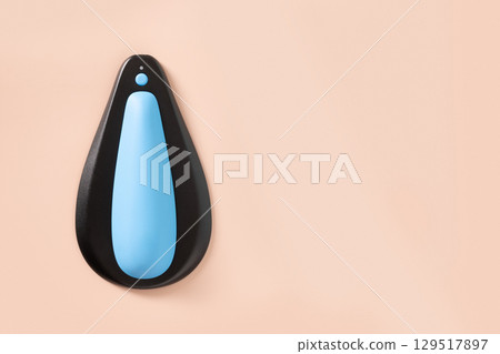 Mens kegel smart trainer with own apps on beige background. Smart trainer for squeeze pelvic floor muscles with biofeedback and vibration. Squeeze force control. Use at home or car. 129517897
