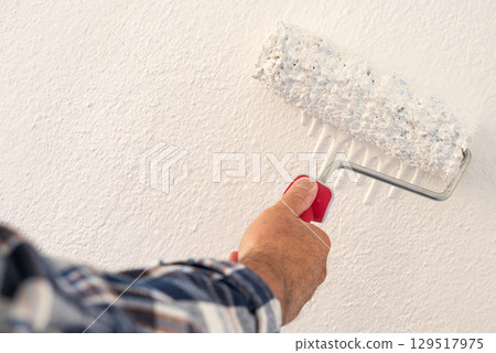 House painter worker painting a wall white. Building. 129517975
