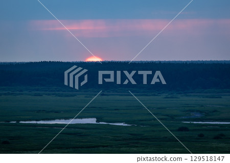 Early sunrise on a misty morning in a field with river and forest on the background. Edge of the sun is rising from behind the trees, begins to lighten the dusk Early sunrise on a misty morning in a field with river and forest on the background. Edge of the sun is rising from behind the trees, begins to lighten the dusk 129518147