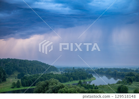 Aerial view of the blue rainy clouds approaching the river. Beautiful landscape of fields, river and hills under the summer strom, gorgeous nature view Aerial view of the blue rainy clouds approaching the river. Beautiful landscape of fields, river and hills under the summer strom, gorgeous nature view 129518148