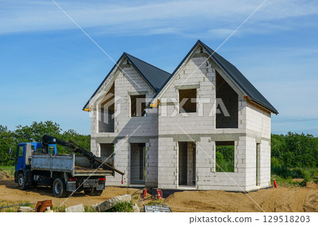 Two-Story House Under Construction with Concrete Blocks and Roof Installed 129518203